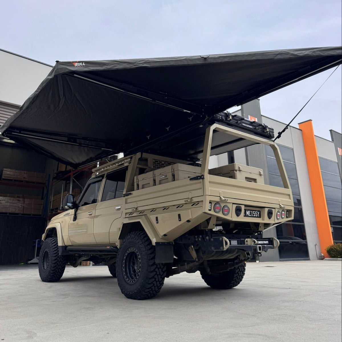 Bull Proof 180 awning open over the side of a sand-coloured Land Cruiser tray ute