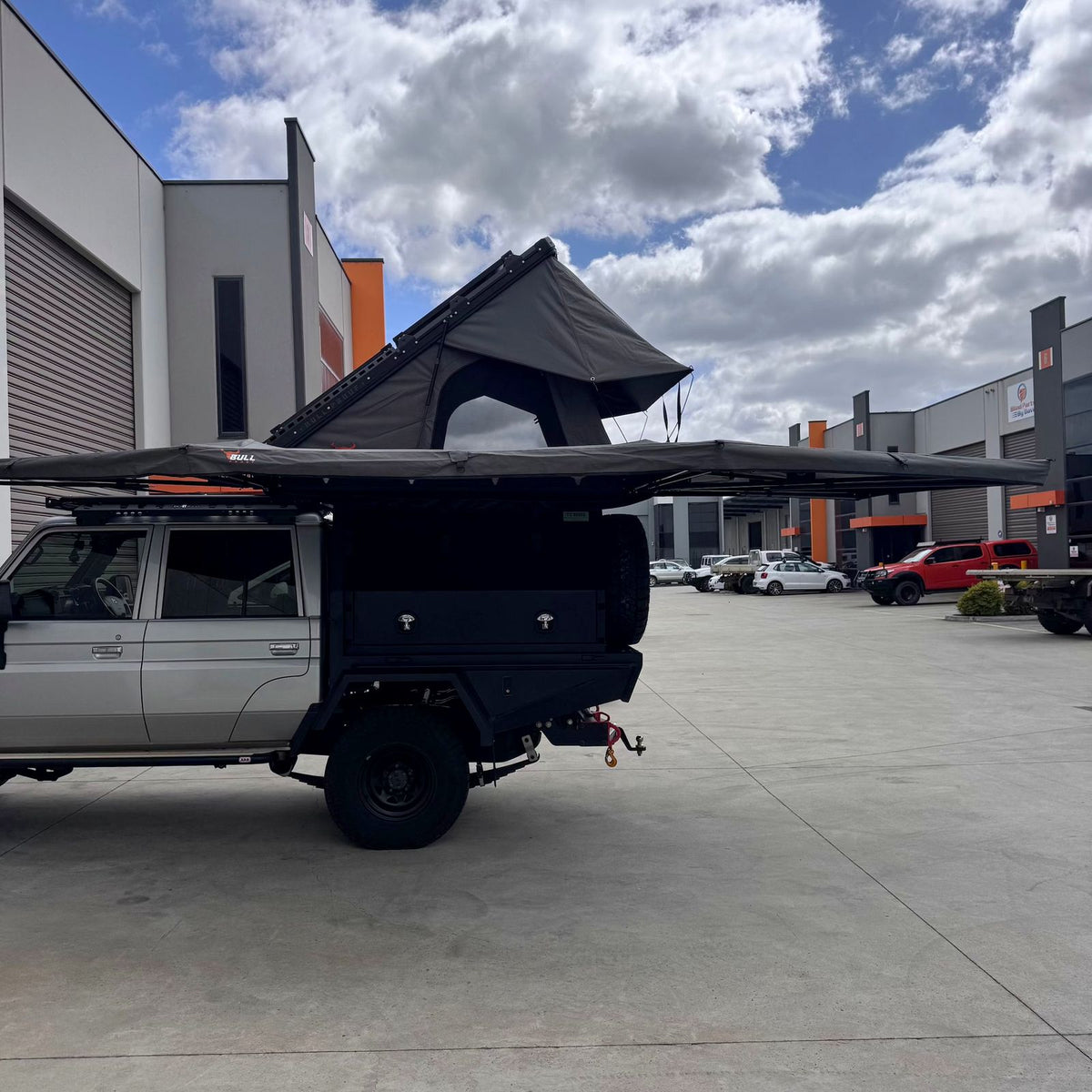 Side view of the 270 XL awning over a Land Cruiser with a hardshell rooftop tent open above the D-zip entry